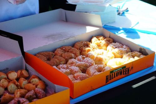 A box of assorted donuts, including glazed, coconut, and cinnamon varieties, with a Halloween-themed design.