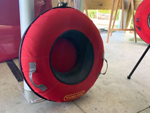 A red inflatable tube with handles, labeled "Tube Pro," resting on a concrete surface.