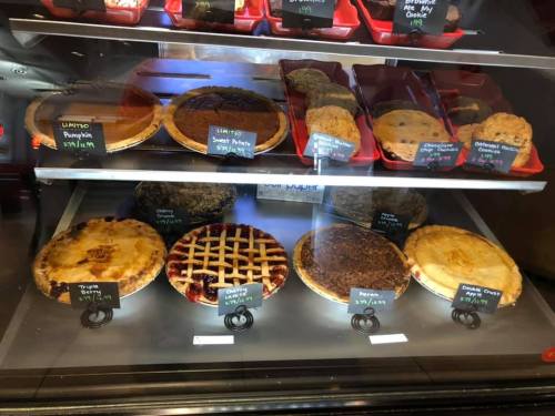 A display case filled with various pies and cookies, including pumpkin, pecan, and cherry pies.