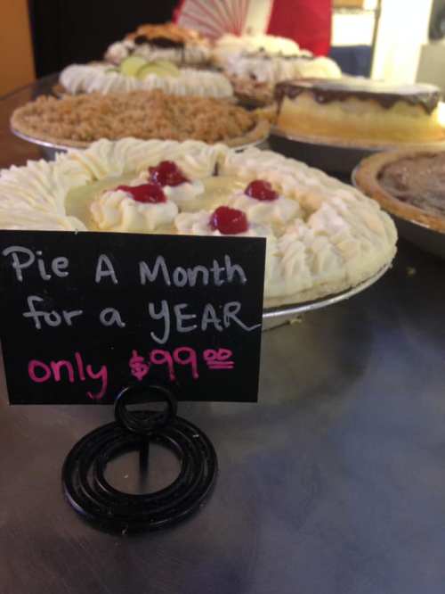 A display of various pies with a sign promoting "Pie A Month for a YEAR" for $99.