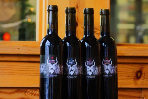 Four bottles of wine with colorful labels, displayed against a wooden background.