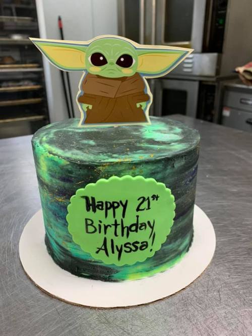 A green and black marbled birthday cake with a Baby Yoda topper and a sign that says "Happy 21st Birthday Alyssa!"