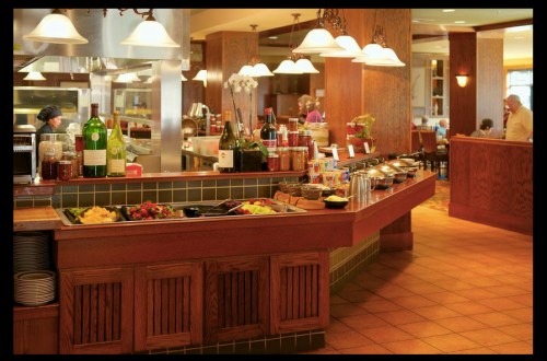 A buffet setup with various dishes and drinks in a warm, inviting restaurant interior.
