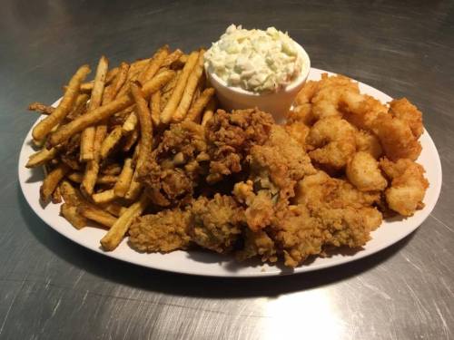 A platter of fried food featuring crispy fries, coleslaw, fried shrimp, and golden-brown chicken pieces.
