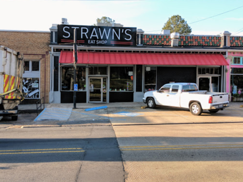 Exterior of Strawn's Eat Shop with a red awning, a white truck parked out front, and a garbage truck nearby.