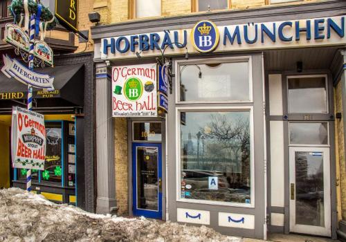 Exterior of Hofbrau München with signs for O'German Beer Hall, featuring snow in front and a vibrant storefront.