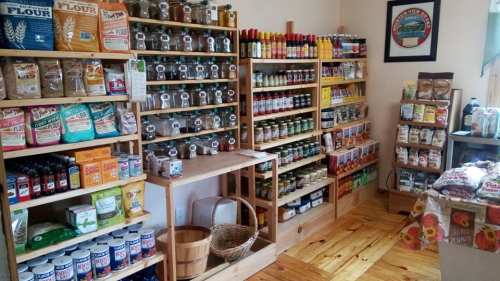 A cozy store interior with wooden shelves filled with jars, spices, and various packaged goods.