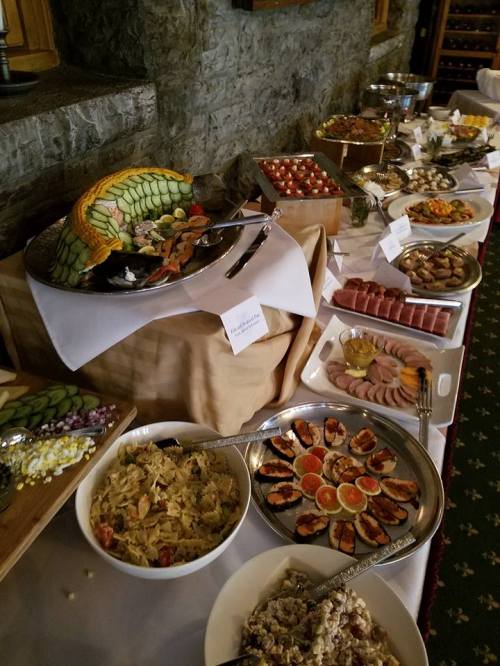 A buffet table featuring a variety of dishes, including pasta, seafood, fruits, and assorted appetizers.