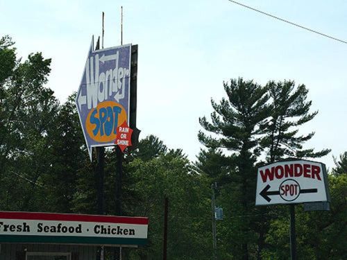 Signage for "Alwagner Spot" and "Wonder Spot," surrounded by trees, indicating a seafood and chicken restaurant.