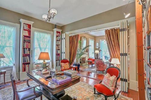 Cozy, well-lit room with bookshelves, a desk, and comfortable seating, featuring large windows and elegant decor.