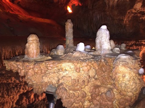 Stalactites and stalagmites in a dimly lit cave, showcasing unique rock formations and textures.