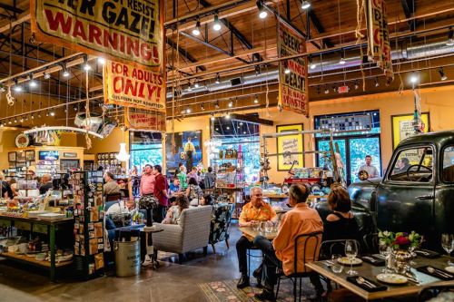 A vibrant indoor market with people dining and shopping, featuring colorful signs and vintage decor.