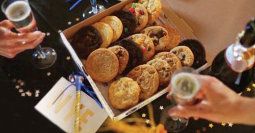 A box of assorted cookies on a table, surrounded by champagne glasses and festive decorations for a celebration.