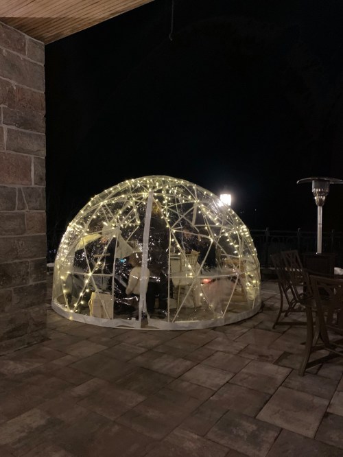 A cozy outdoor igloo with string lights, set on a stone patio at night.