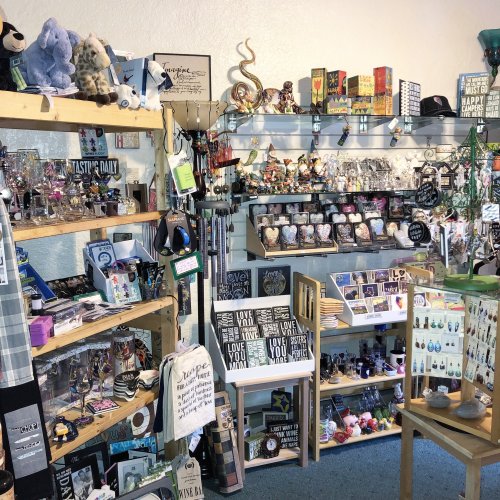 A cozy gift shop filled with various items, including plush toys, decor, and souvenirs on wooden shelves.
