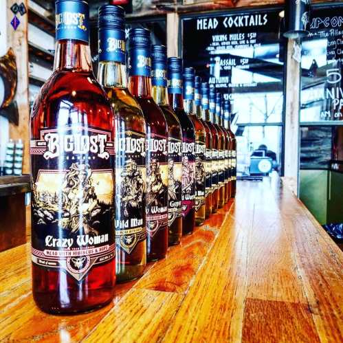 A row of bottles labeled "Boldt" with flavors like "Crazy Woman" and "Wild Man" on a wooden bar.