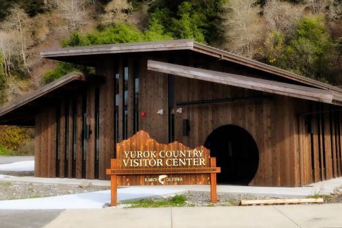 Yurok Country Visitor Center building with wooden architecture, surrounded by greenery in Klamath, California.