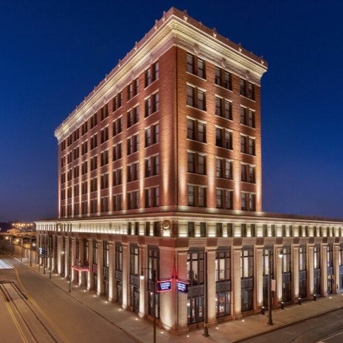 Historic brick building illuminated at night, featuring multiple floors and elegant architectural details.