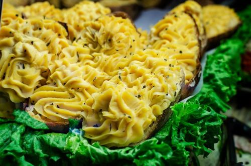 A close-up of decorative mashed potatoes on bread, garnished with herbs, resting on a bed of lettuce.