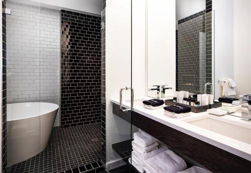 Modern bathroom featuring a freestanding tub, sleek black tiles, and a stylish vanity with neatly arranged towels and toiletries.