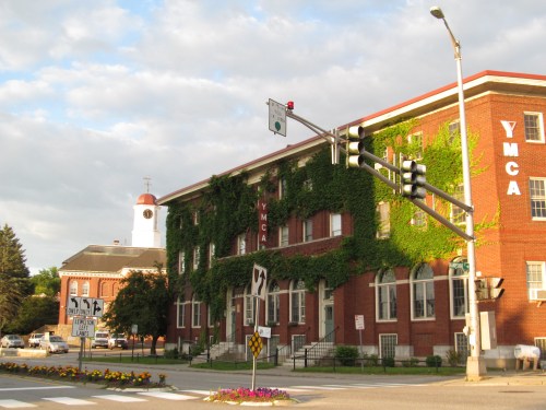 Historic YMCA building covered in green ivy, with traffic lights and a clock tower in the background.