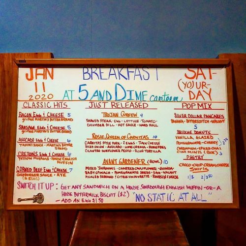 Menu board for a diner featuring breakfast and lunch items, including pancakes, sandwiches, and daily specials.