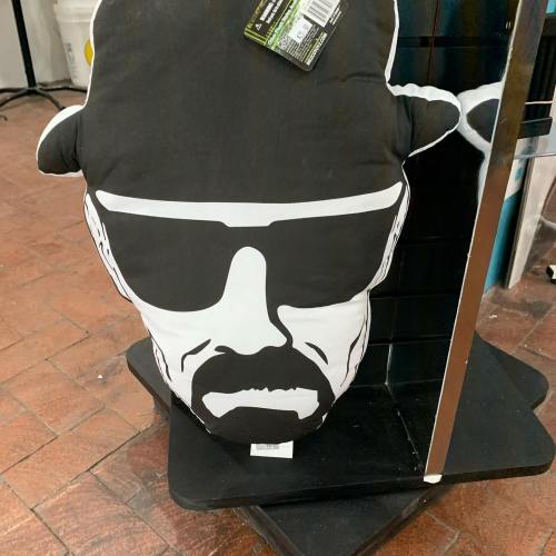 A black and white pillow shaped like a character wearing sunglasses and a hat, displayed on a shelf.