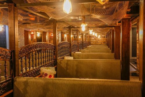 Cozy restaurant interior with wooden booths, warm lighting, and decorative netting overhead.