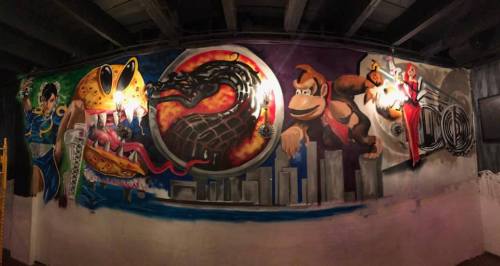 Colorful mural featuring iconic video game characters, including a dragon, a frog, and Donkey Kong, on a wall.