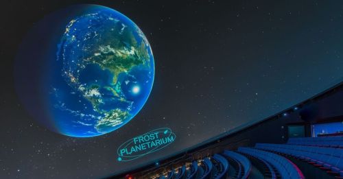 A view of Earth from a planetarium, with seating below and "Frost Planetarium" displayed on the floor.