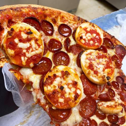 A slice of pizza topped with pepperoni and stuffed bread bites filled with cheese and sauce.