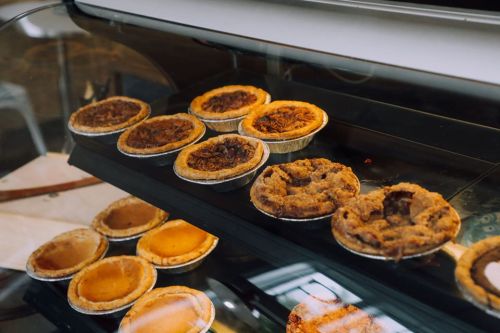 A display case filled with various baked pies in individual crusts, showcasing different flavors and textures.