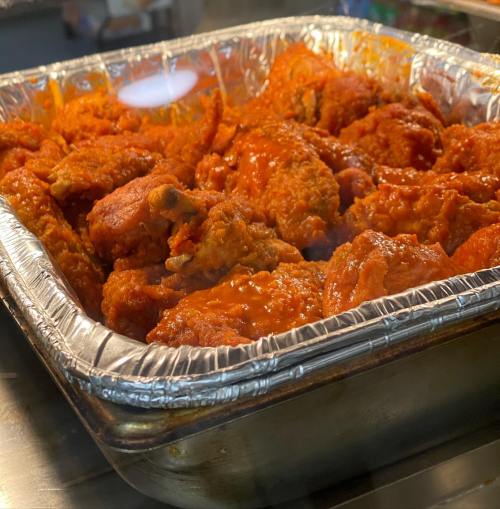 A tray of spicy, sauced chicken wings, glistening and piled high.
