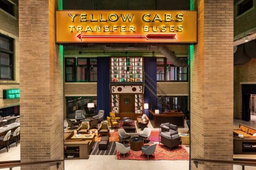 A stylish interior featuring a retro sign for "Yellow Cabs" and "Transfer Buses," with cozy seating and modern decor.