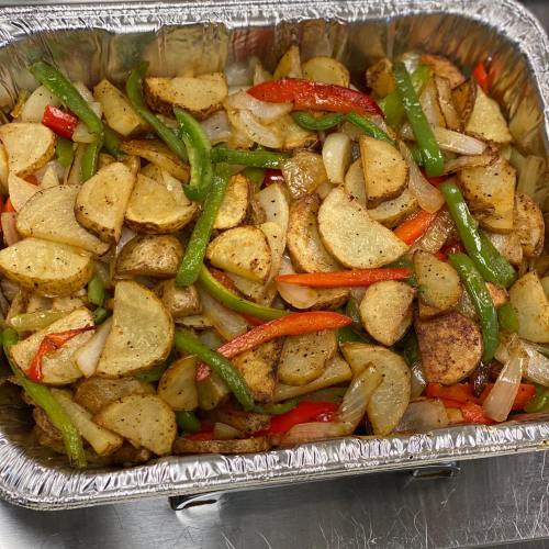 A tray of roasted potatoes mixed with red and green bell peppers and onions, seasoned and golden brown.