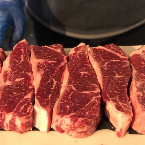 Close-up of several marbled beef steaks arranged on a cutting board, showcasing rich red and white fat.
