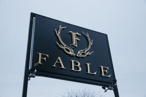 Sign for "FABLE" featuring a stylized letter "F" and antlers, set against a gray sky.