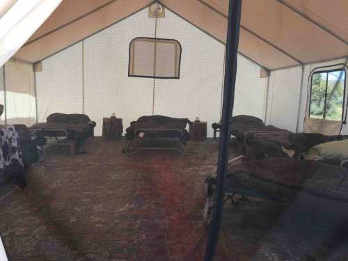 Interior of a tent with several cots arranged on a patterned rug, creating a cozy sleeping area.