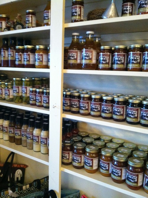A shelf filled with various jars and bottles of sauces and condiments, all neatly organized.