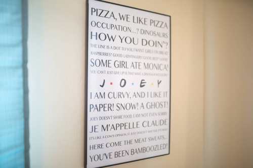 A framed poster with humorous text about pizza, dinosaurs, and playful phrases in various fonts and languages.