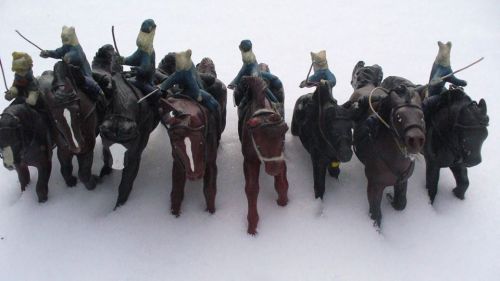 A lineup of toy soldiers on horseback, each wearing a unique outfit, set against a snowy background.