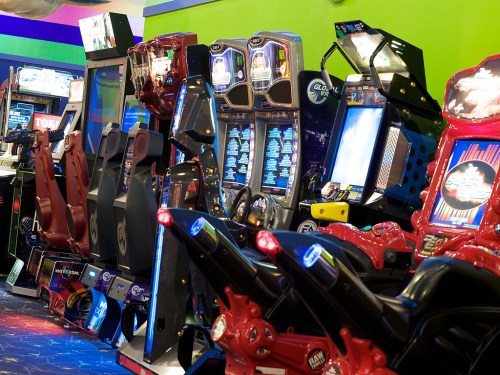 A row of colorful arcade games with various controls and screens in a vibrant gaming environment.