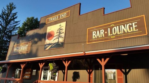 Exterior of a building with signs for "Trails End," "Restaurant," and "Bar Lounge," surrounded by trees.