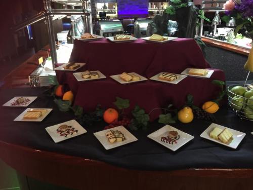 A display of assorted desserts on white plates, arranged on a tiered table with fruits and decorative elements.