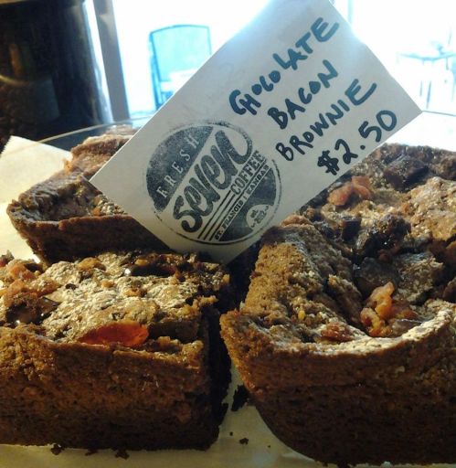 A display of chocolate bacon brownies with a price tag of $2.50 at a coffee shop.