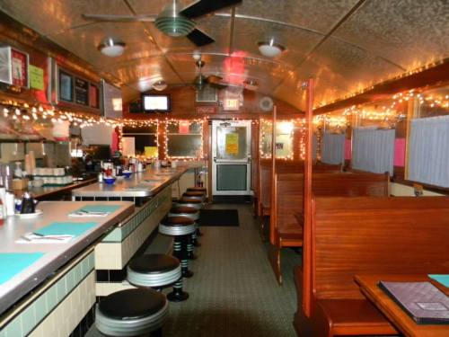A cozy diner interior with a long counter, booths, and warm lighting, creating a welcoming atmosphere.