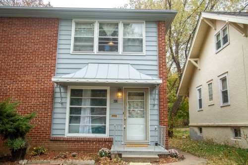 A two-story house with a brick and blue exterior, featuring a front porch and a small garden.