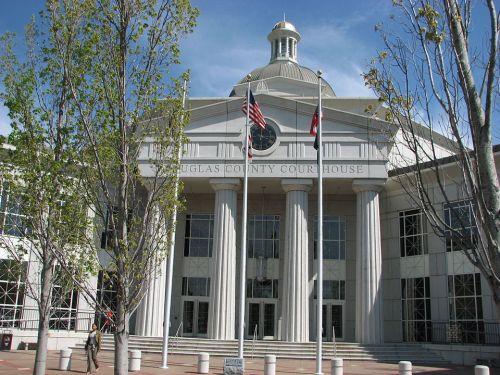 Front view of the Douglas County Courthouse, featuring columns, flags, and a dome under a clear blue sky.