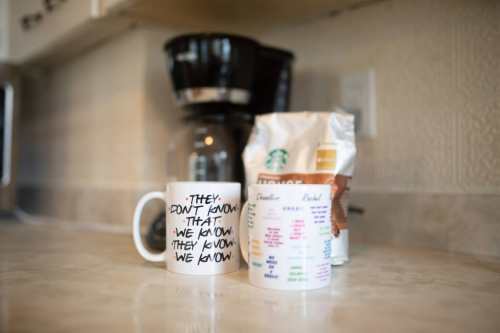 A coffee mug with a quote sits next to a bag of Starbucks coffee on a kitchen counter.
