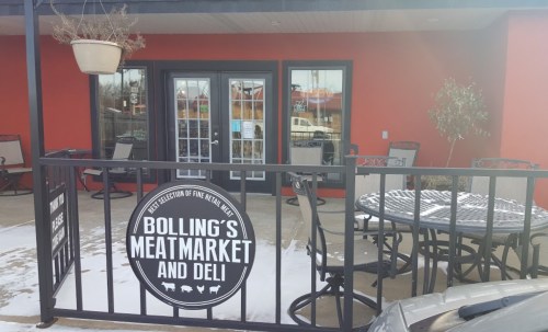 Exterior view of Bolling's Meat Market and Deli, featuring a sign and outdoor seating area.
